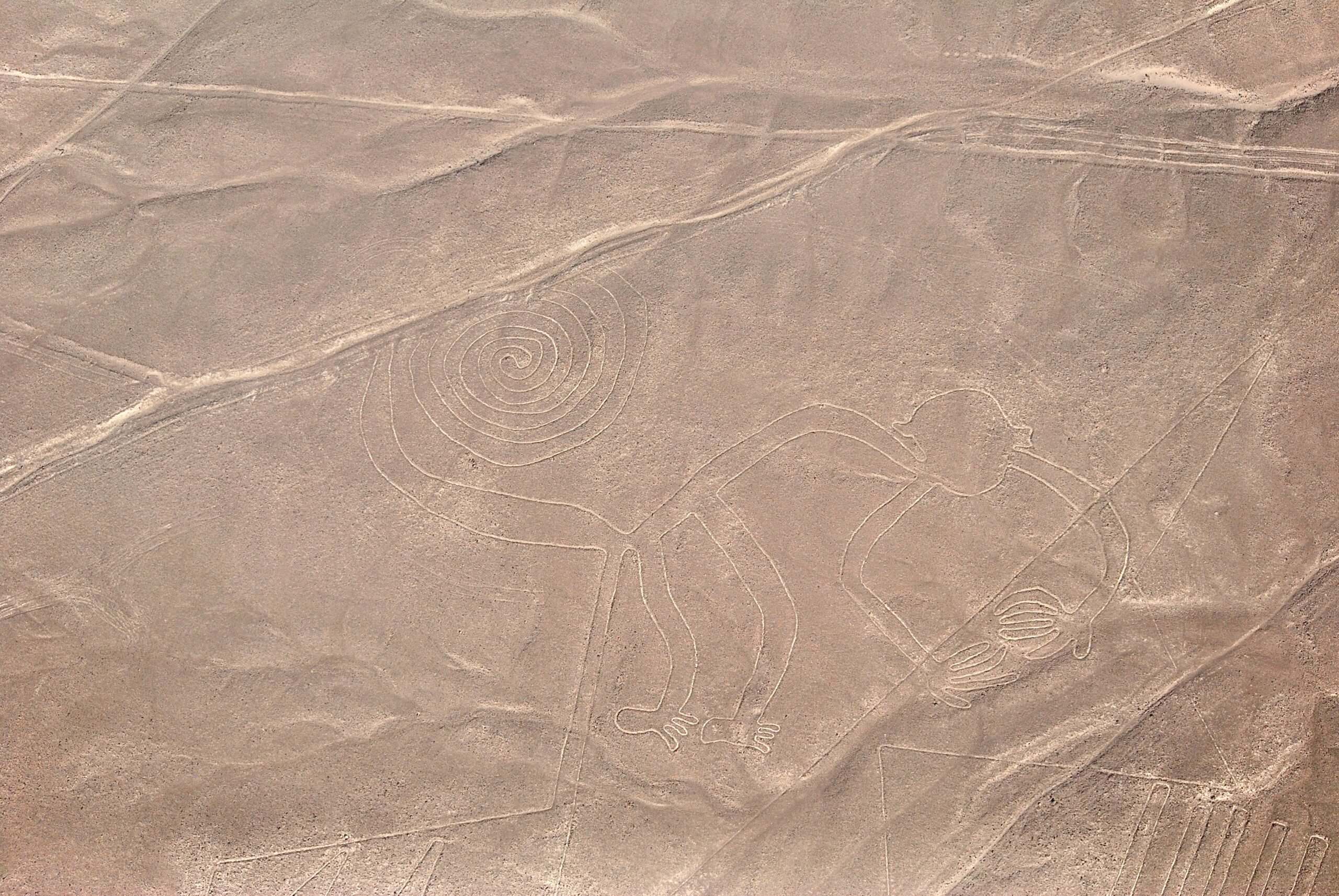 A stunning aerial capture of the iconic Nazca Lines, including the spiral and monkey figures, in Peru's desert landscape.