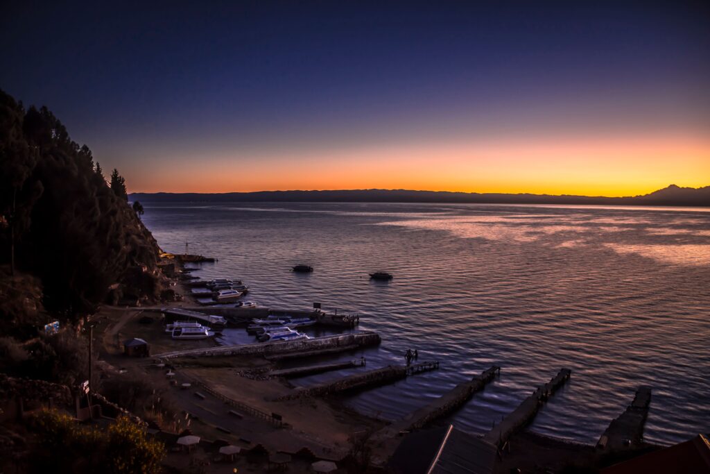 Stunning sunset view over Lake Titicaca from Copacabana, Bolivia with tranquil water and vibrant sky.